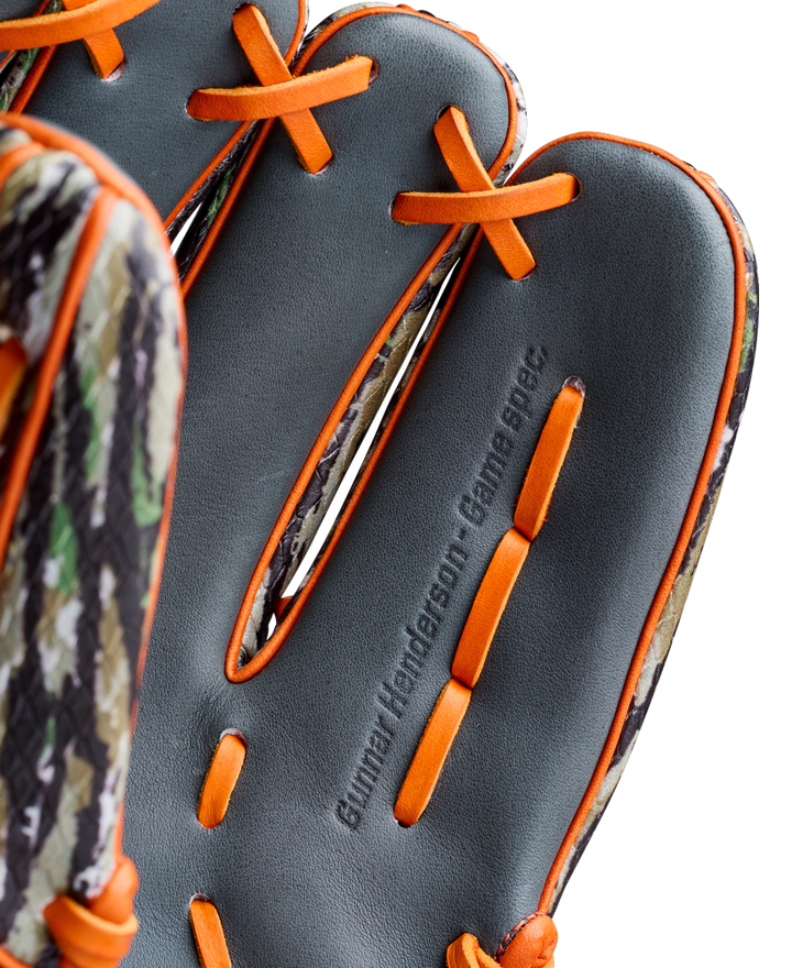 Close-up of the Wilson A2000 GH2 11.75" Gunnar Henderson GM Baseball Glove’s palm, showing orange laces, a camouflage edge, and the “Gunnar Henderson - Game Spec.” embossing. Model: WBW1034511175.