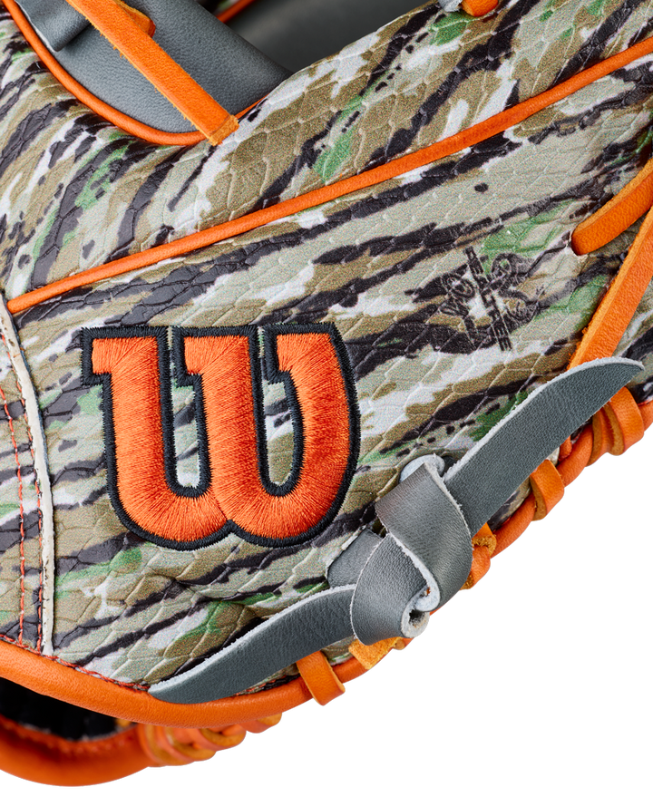A close-up of the Wilson A2000 GH2 11.75" Gunnar Henderson GM Baseball Glove, showcasing its camouflage design with orange trim and a prominent orange and black Wilson "W" logo on the side.