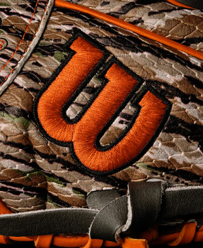 Close-up of a Wilson A2000 GH2 11.75" Gunnar Henderson GM Baseball Glove (WBW1034511175) with a camouflage pattern, orange embroidered W logo, orange stitching, and black and gray leather details.