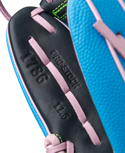 Close-up of the Wilson A2000 1786SS 11.5" GOTM March 2025 baseball glove in blue with black Pro Stock leather, pink lacing, green edge stitching, and embossed text: PRO-STOCK, 1786, and 11.5.