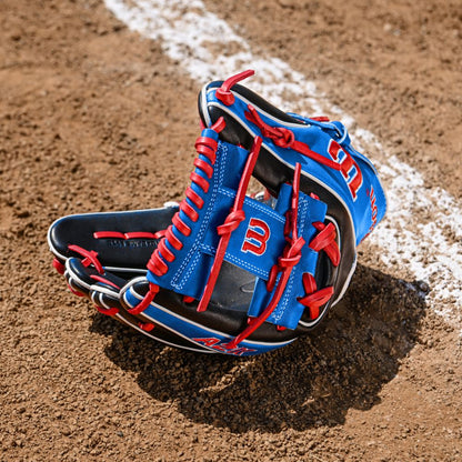 A Wilson A2K MB1175 11.75" Mookie Betts Gameday Baseball Glove (FALL 2025, WBW1035001175) with blue and red Pro Stock Select leather and white stitching rests on dirt by a chalk baseline.