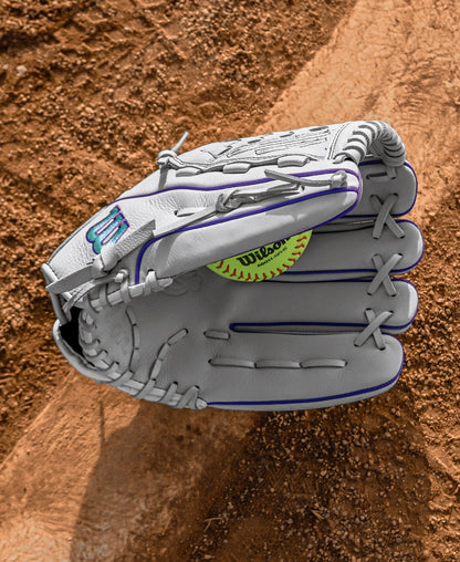 A Wilson A500 Siren 12.5" Fastpitch Glove by Wilson, made of top grain leather, catches a yellow softball on a dirt baseball field.