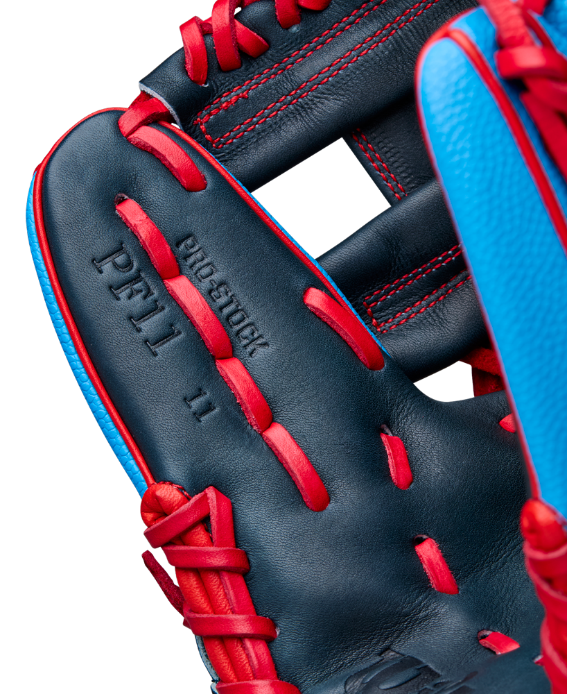 Close-up of the Wilson A2000 PF11SS 11" Baseball Glove (WBW10394011), a dark blue infield glove with bright red laces and stitching, light blue accents, and “PF11 11” and “PRO STOCK” embossing. Made from Pro Stock leather.