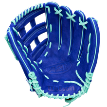 A Wilson A2K JS22 12.75" Juan Soto GM Baseball Glove by Wilson, featuring blue Pro Stock Select leather with mint green laces and accents, is displayed open with the palm facing up against a white background.