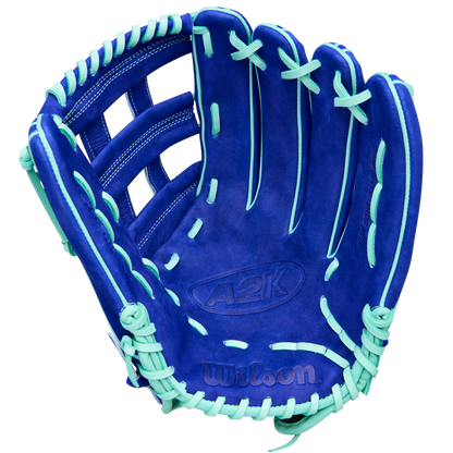 A Wilson A2K JS22 12.75" Juan Soto GM Baseball Glove by Wilson, featuring blue Pro Stock Select leather with mint green laces and accents, is displayed open with the palm facing up against a white background.