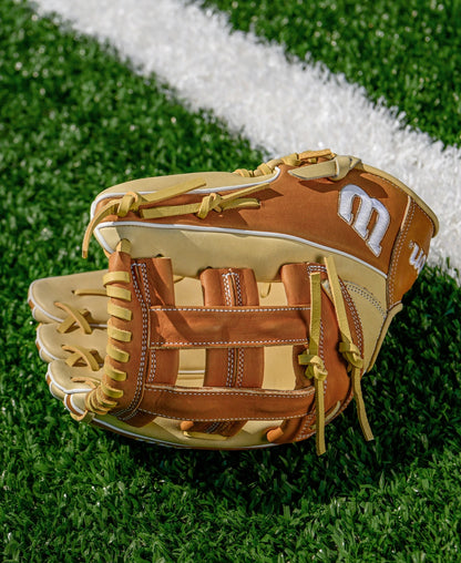 A Wilson A1000 1750 12.5" Baseball Glove (WBW103964125) in brown and tan sits on green artificial turf near a white line.