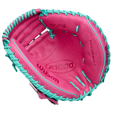 A Wilson A1000 CM33 33" Baseball Catcher's Mitt (WBW10396633) in pink with teal laces, seen from above to reveal the palm and interior branding. Crafted from full grain leather by Wilson.
