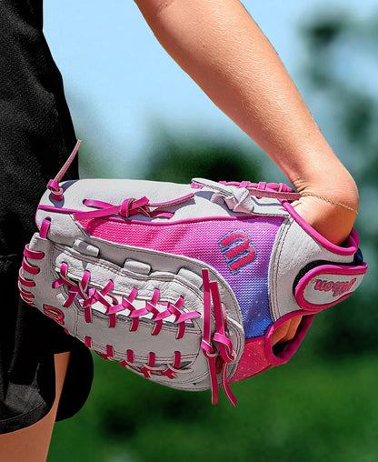 A person holds a Wilson Flash 12" Fastpitch Glove (WBW10398712) with gray, pink, and purple colors and bright pink laces outdoors on a sunny day. The glove is worn on their left hand.