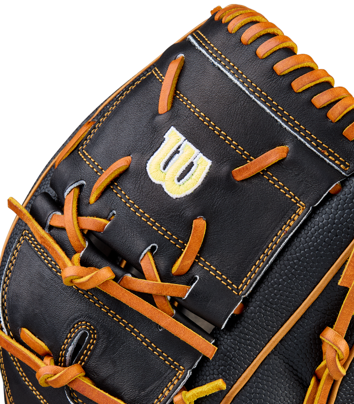 Close-up of a black Wilson A2000 B125SS 12.5" Baseball Glove (WBW104119125) with orange laces, yellow stitching, and a bold white and yellow W logo embroidered on a rectangular leather patch.