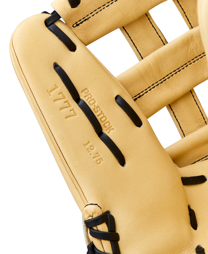 Close-up of a Wilson A2000 1777 12.75" Baseball Glove (WBW1041231275) outfield glove in tan with black laces. Stamped text reads 1777, Pro Stock, and 12.75 on the Pro Stock Leather; stitching and texture are clearly visible.