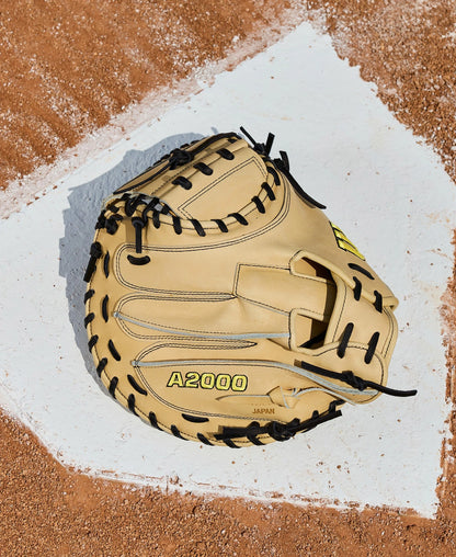 A Wilson A2000 1734 34" Baseball Catcher's Mitt (WBW10412934) in beige and black Pro Stock Leather rests on home plate, surrounded by brown dirt.