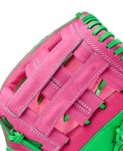 Close-up of a Wilson A2000 JR11 12" José Ramírez GM Baseball Glove (WBW10413512) with pink leather, green laces, white stitching, SuperSkin accents, and basket-weave web on a plain white background.