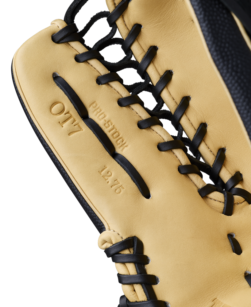 A close-up of a tan and black Wilson A2000 OT7SS 12.75" Baseball Glove, highlighting its detailed stitching, black laces, and embossed text—PRO STOCK, OT7, and 12.75—on the leather.