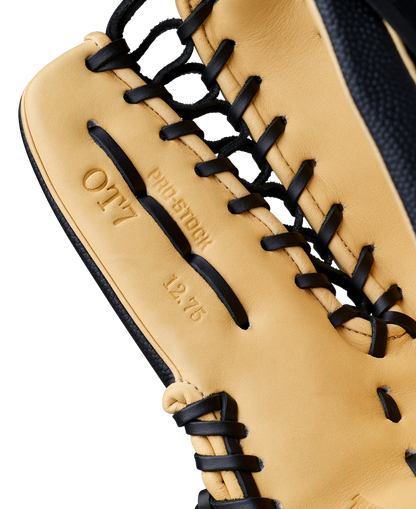 A close-up of a tan and black Wilson A2000 OT7SS 12.75" Baseball Glove, highlighting its detailed stitching, black laces, and embossed text—PRO STOCK, OT7, and 12.75—on the leather.