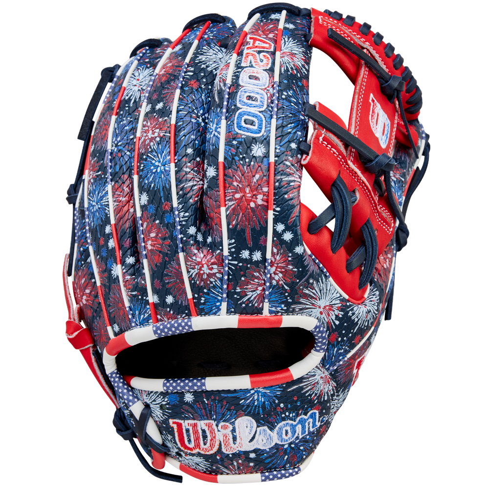 The Wilson A2000 1975SS 11.75" Baseball Glove (GOTM July 2025) features Pro Stock leather and a red, white, and blue fireworks design with stars, stripes, and the Wilson logo on the wrist.