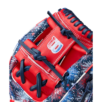 Close-up of the Wilson A2000 1975SS 11.75" Baseball Glove - GOTM July 2025, featuring red, white, and blue Pro Stock leather, navy laces, detailed stitching, the Wilson logo on the strap, and a vibrant fireworks pattern.