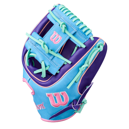 The Wilson A2K 1720 11.5" Baseball Glove (GOTM October 2025, WBW104220115) features blue, purple, and pink Pro Stock Select leather with teal laces and a pink Wilson logo on the wrist and thumb.