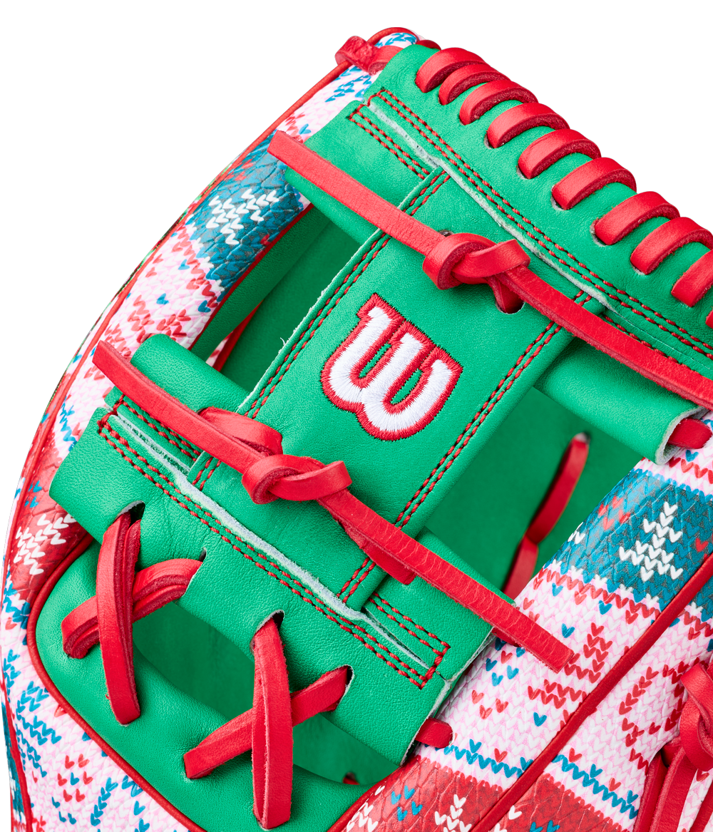 A close-up of the Wilson A2000 1975 11.75" Baseball Glove (GOTM December 2025, WBW1042211175) showcases green Pro Stock leather, red laces, a red-and-white knit holiday sweater design, and a white-and-red stitched Wilson W logo.