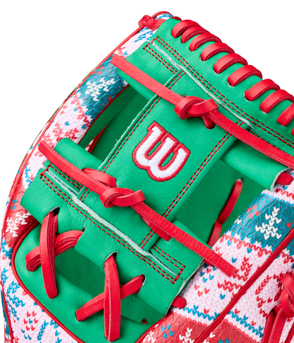 A close-up of the Wilson A2000 1975 11.75" Baseball Glove (GOTM December 2025, WBW1042211175) showcases green Pro Stock leather, red laces, a red-and-white knit holiday sweater design, and a white-and-red stitched Wilson W logo.