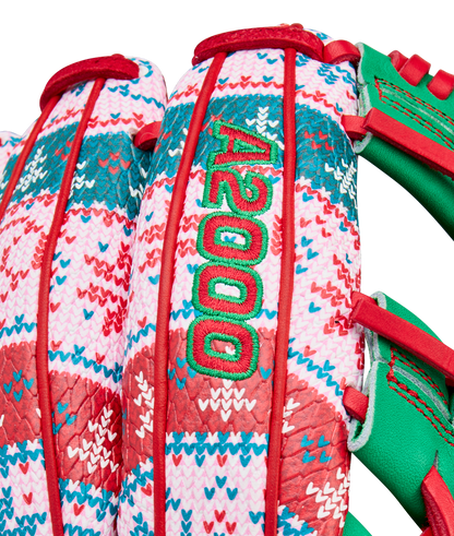 Close-up of the Wilson A2000 1975 11.75" Baseball Glove (GOTM Dec 2025), featuring a colorful holiday red, green, pink, and white woven pattern, green embroidered A2000 text, red laces, green leather accents, and Pro Stock leather.