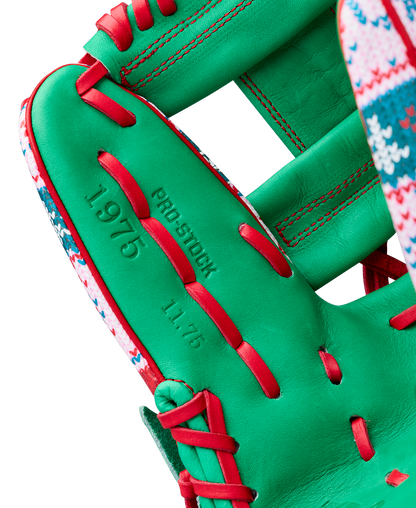 A close-up of the Wilson A2000 1975 11.75" Baseball Glove (GOTM December 2025) shows its green Pro Stock leather, red laces, and festive trim, with "PRO STOCK," "1975," and "11.75" stamped on the glove.