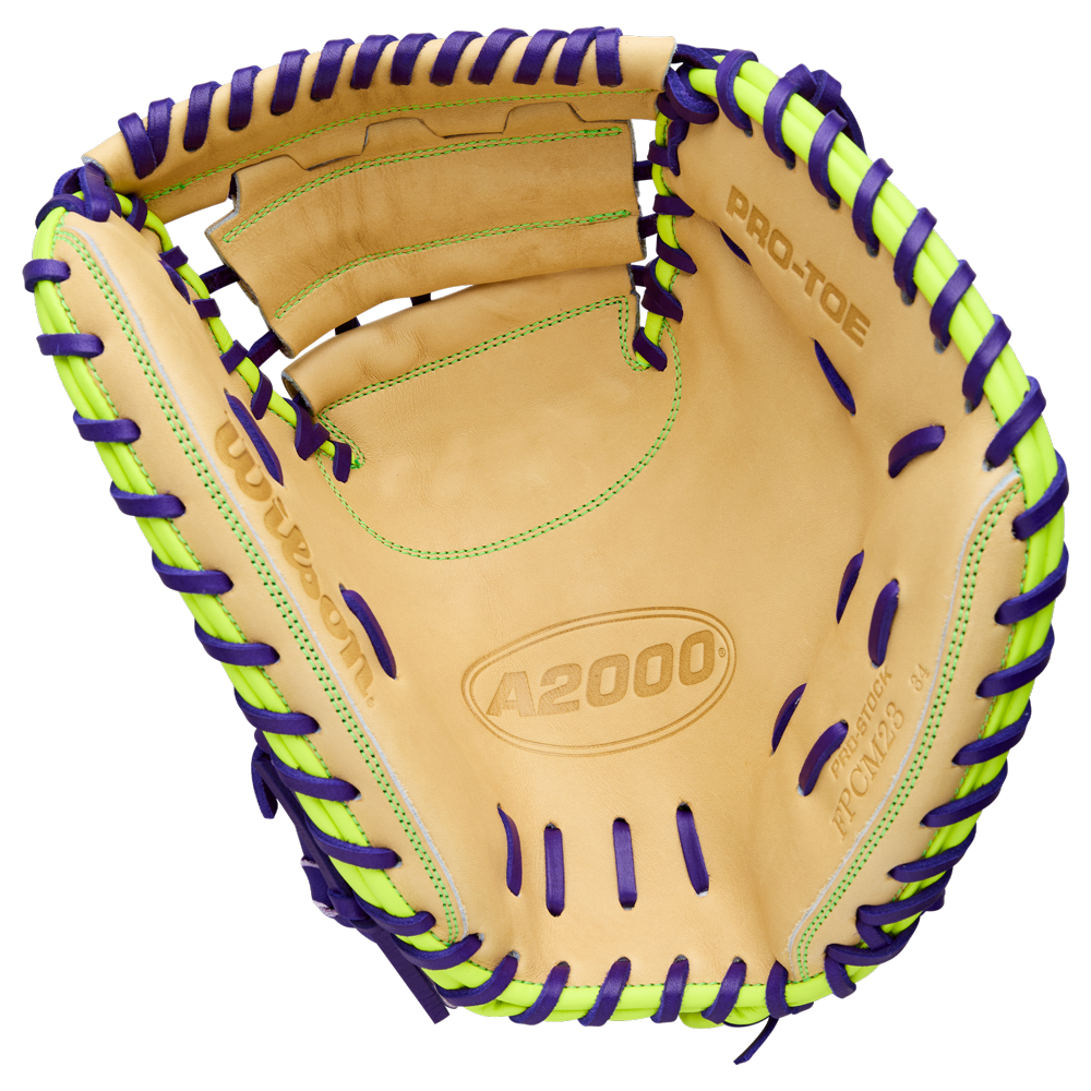 The Wilson A2000 FPCM23 34" Fastpitch Catcher's Mitt (WBW10423934) is a tan glove with purple and neon green laces, “A2000” and “PRO-TOE” on the inside. Made from Pro Stock leather, it features visible stitching and an open web design.