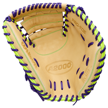 The Wilson A2000 FPCM23 34" Fastpitch Catcher's Mitt (WBW10423934) is a tan glove with purple and neon green laces, “A2000” and “PRO-TOE” on the inside. Made from Pro Stock leather, it features visible stitching and an open web design.