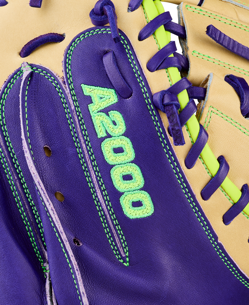 Close-up of the Wilson A2000 FPCM23 34" Fastpitch Catcher's Mitt (WBW10423934) featuring purple and tan Pro Stock leather, neon green stitching, purple laces, and green embroidered A2000 text on the purple section.