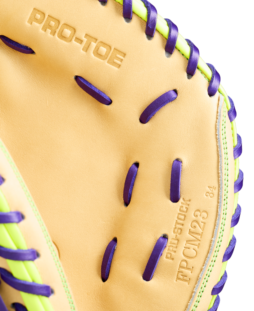 Close-up of a Wilson A2000 FPCM23 34" Fastpitch Catcher's Mitt (WBW10423934) featuring tan Pro Stock leather, purple laces, green accents, and embossed text: PRO-TOE, PRO-STOCK, FPCM23, and the number 34.