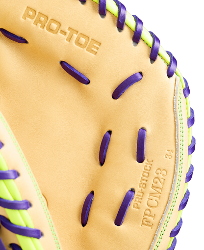 Close-up of a Wilson A2000 FPCM23 34" Fastpitch Catcher's Mitt (WBW10423934) featuring tan Pro Stock leather, purple laces, green accents, and embossed text: PRO-TOE, PRO-STOCK, FPCM23, and the number 34.
