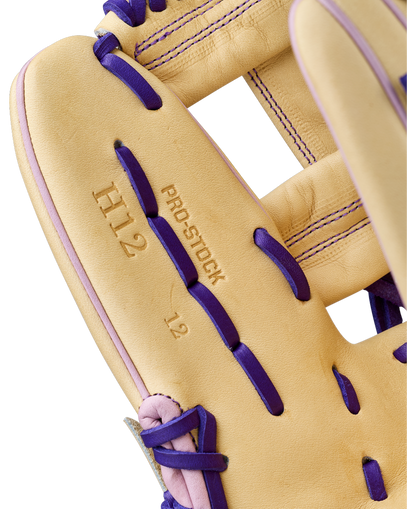 Close-up of a tan Wilson A2000 H12 12" Fastpitch Glove (WBW10460712) with purple laces and stitching. The infield glove features PRO STOCK, H12, and 12 stamped on the palm, showcasing premium Pro Stock Leather.