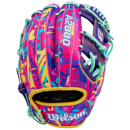 The Wilson A2000 1786SS 11.5" GOTM January 2026 baseball glove features bold abstract pink, yellow, teal, and purple patterns, teal lacing, durable SuperSkin material, and "A2000" and "Wilson" in white.