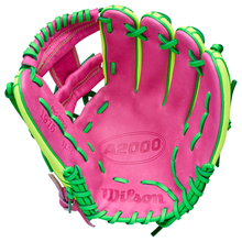 The Wilson A2000 1975SS 11.75" Baseball Glove GOTM March 2026 features a pink design with green and yellow laces, visible stitching, embossed palm branding, and is crafted from premium Pro Stock Leather.