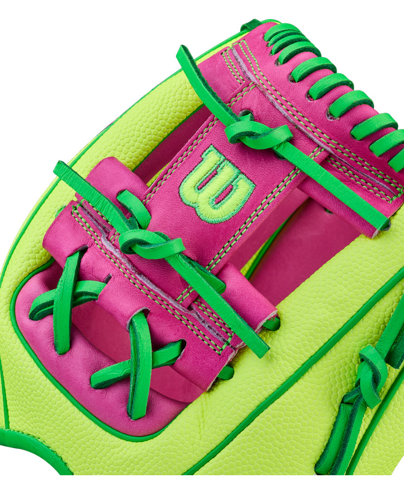 A close-up of a Wilson A2000 1975SS 11.75" GOTM March 2026 baseball glove in neon green and pink with green laces, pink leather, and a stitched W logo, inspired by product WBW1046441175.