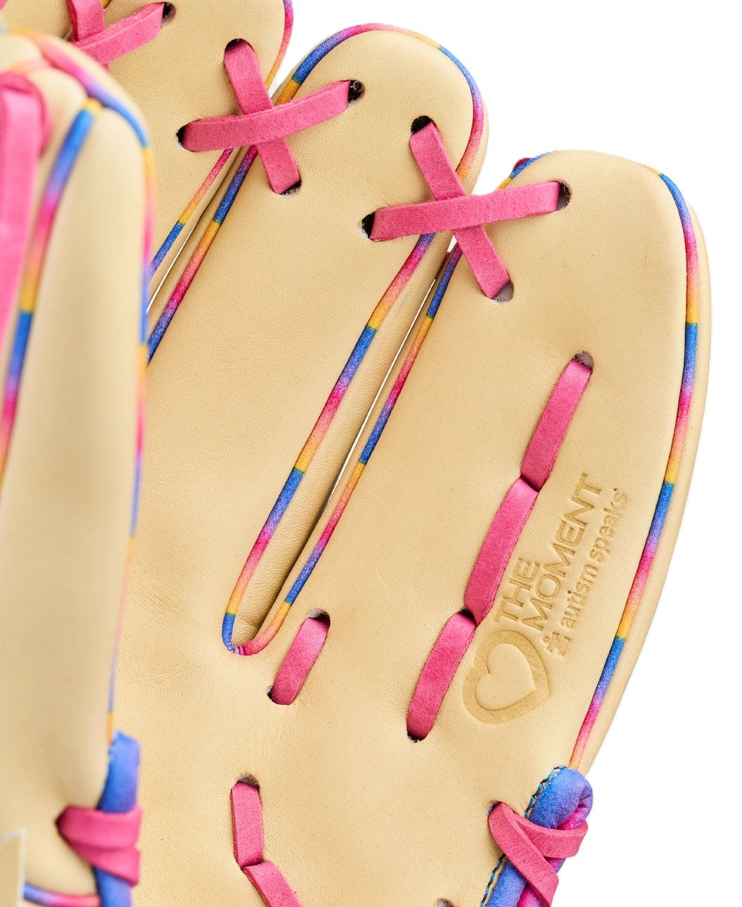 A close-up of the Wilson Love the Moment A2000 1786 11.5" beige baseball glove with pink and multicolored laces, featuring an embossed "THE MOMENT catching sparks" logo and a heart symbol.
