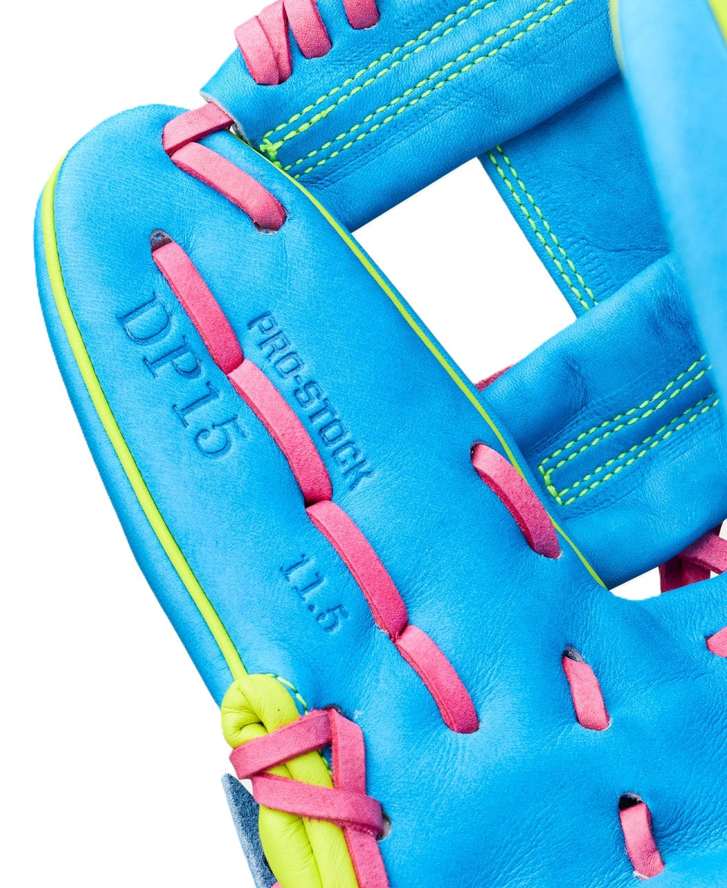 Close-up of the Wilson Love the Moment A2000 DP15 11.5" baseball glove in blue with pink laces and yellow-green accents, featuring visible stitching and "DPLD" embossed on Pro Stock leather. Model: WBW104828115.