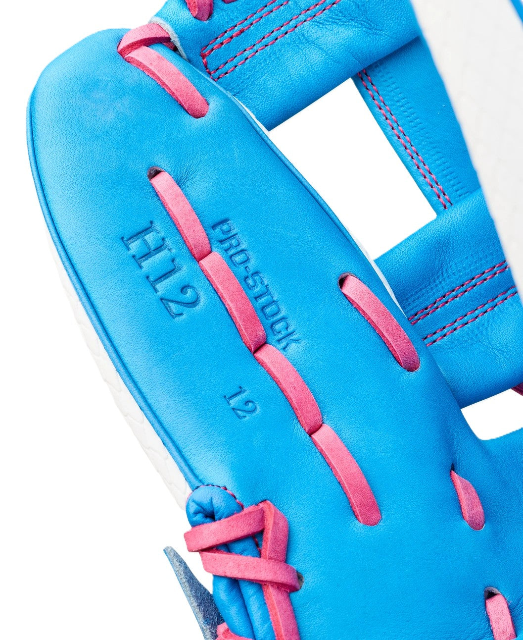 Close-up of the Wilson Love the Moment A2000 H12SS 12" Fastpitch Glove (WBW10483612) in blue with pink laces, featuring "H12," "PRO-STOCK," and "12" stamped on the inner palm area.