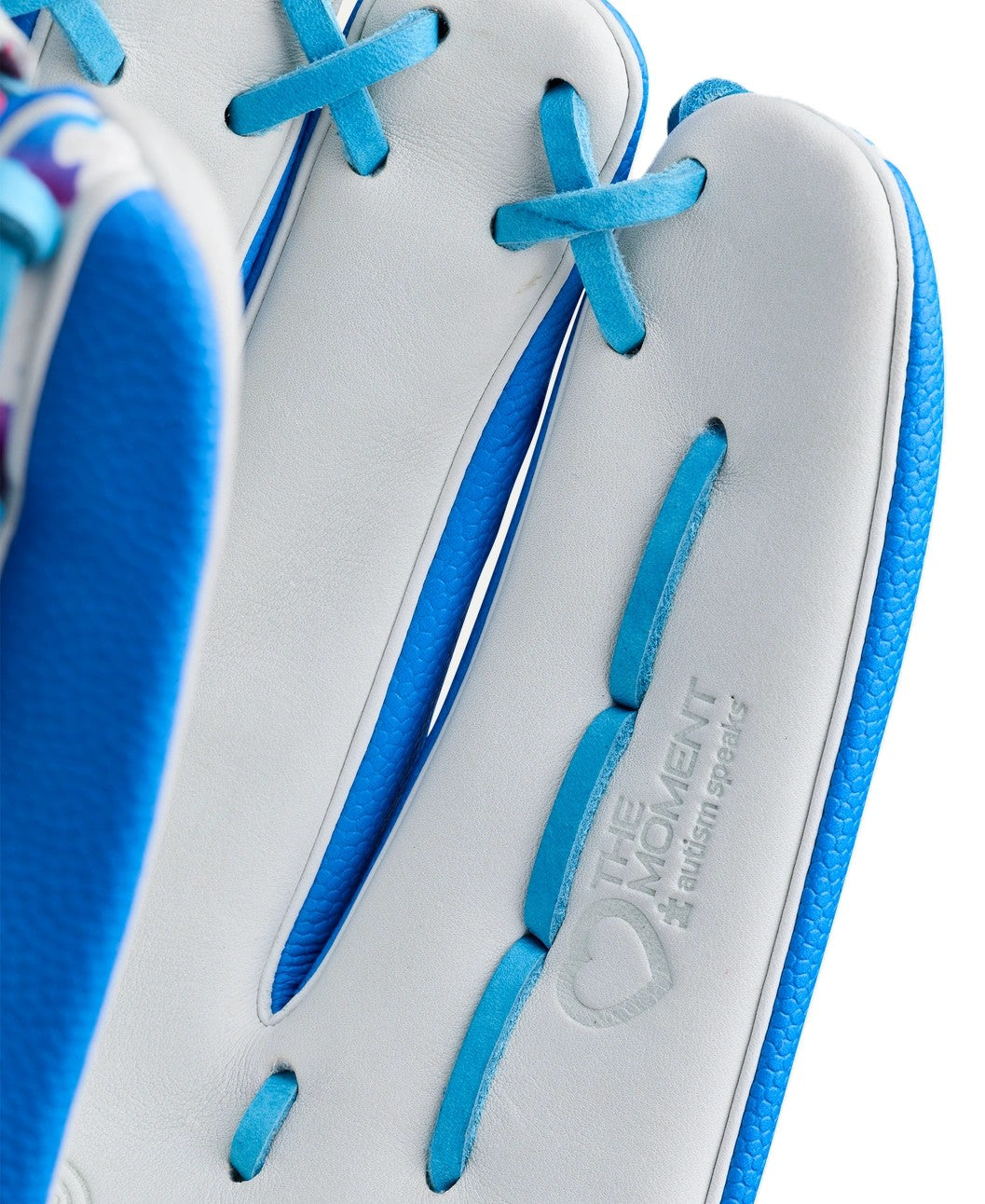 Close-up of the Wilson Love the Moment A2000 T125SS 12.5" Fastpitch Glove, showcasing white and blue leather, detailed stitching, laces, and THE MOVEMENT Autism Speaks embossed near a heart logo—crafted in classic Wilson style.