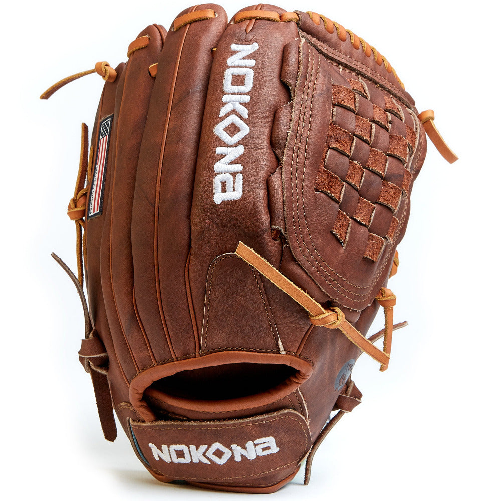 The Nokona Walnut 12" Fastpitch Glove (W-V1200C) features brown leather, white embroidered branding, an American flag patch, and tan laces—showcasing its premium handcrafted webbing and pocket.