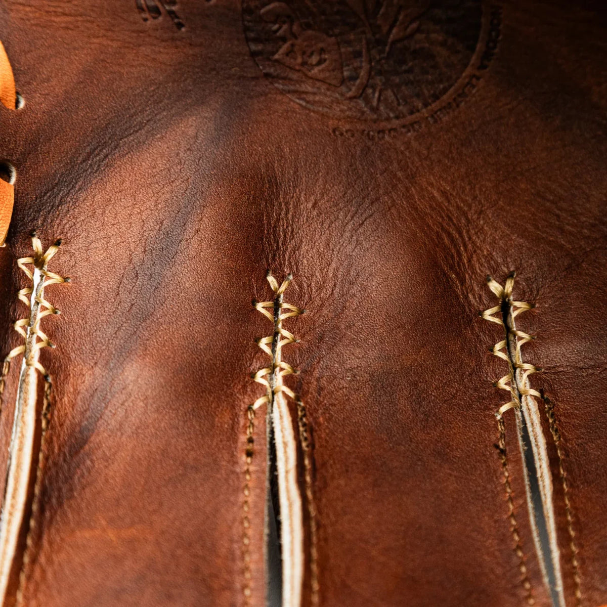 Close-up of a Nokona Walnut EP 11.5″ Baseball Glove: W-EP1150 showing the lacing between the fingers and a logo stamped into the handcrafted leather.