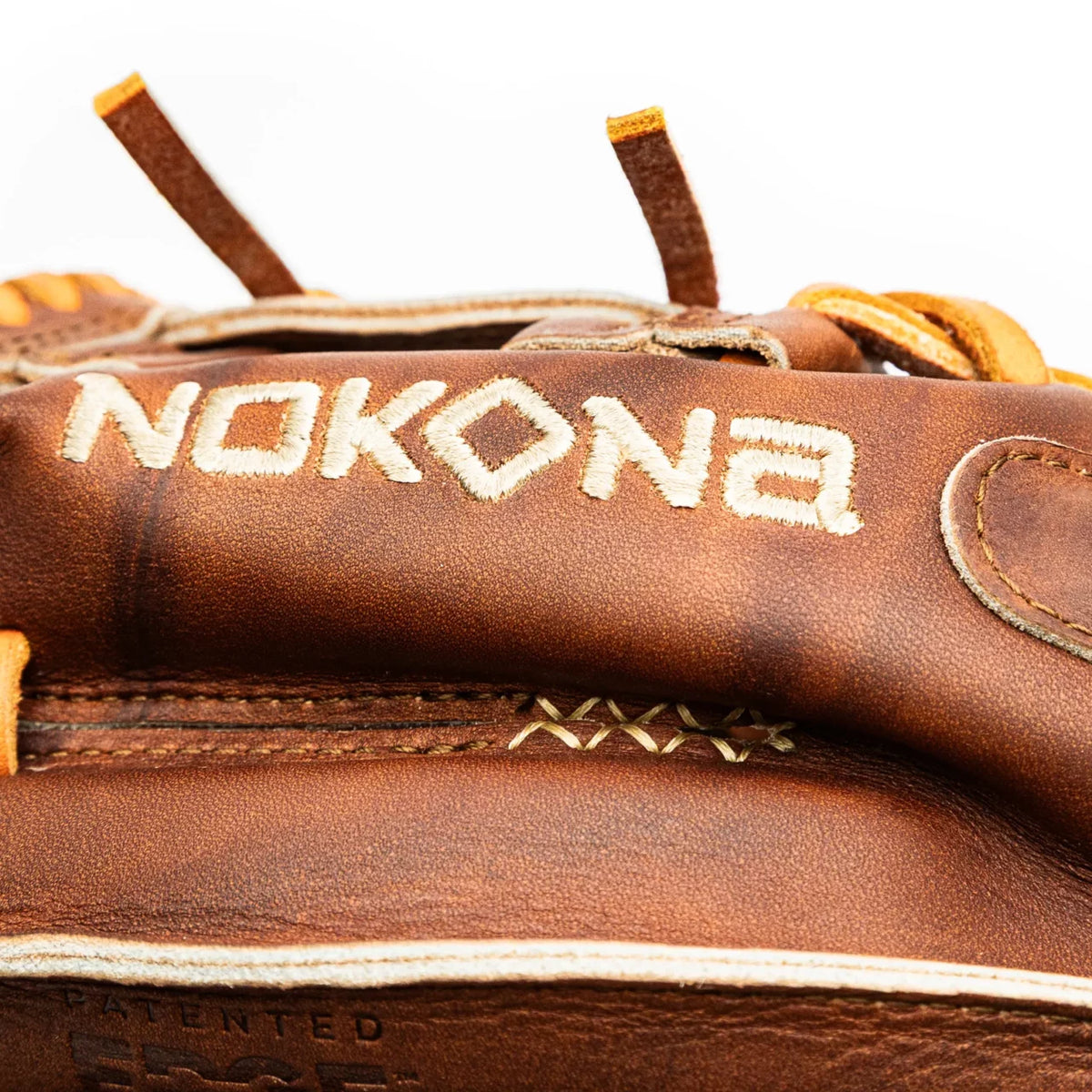 Close-up of a brown leather Nokona Walnut EP 11.5″ Baseball Glove: W-EP1150 featuring embroidered brand text on the back of the wrist strap.