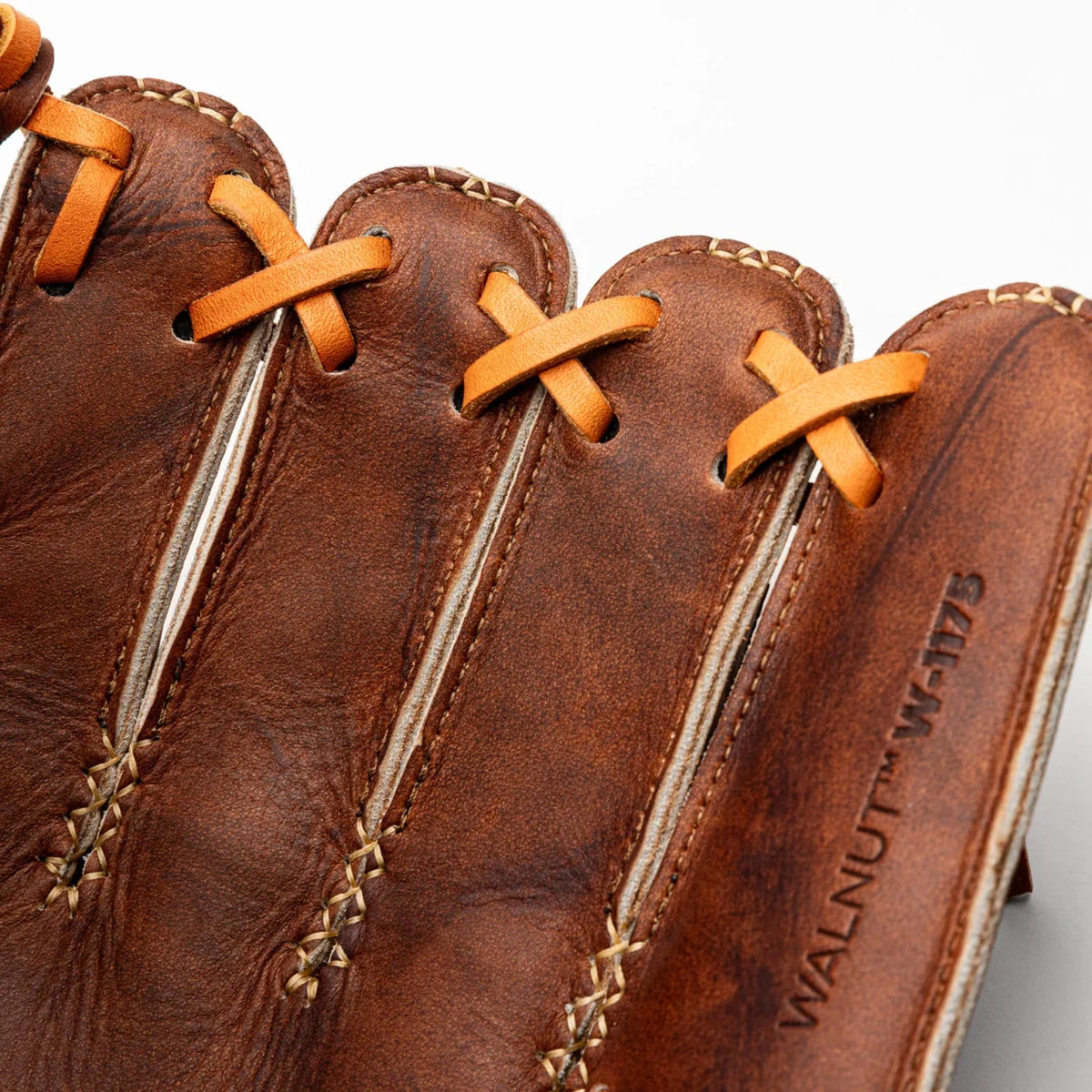 Close-up of a brown leather Nokona Walnut EP 11.75″ Baseball Glove: W-EP1175 with tan laces, showing the fingers and the stamped text WALNUT W-1175 on the handcrafted baseball glove.