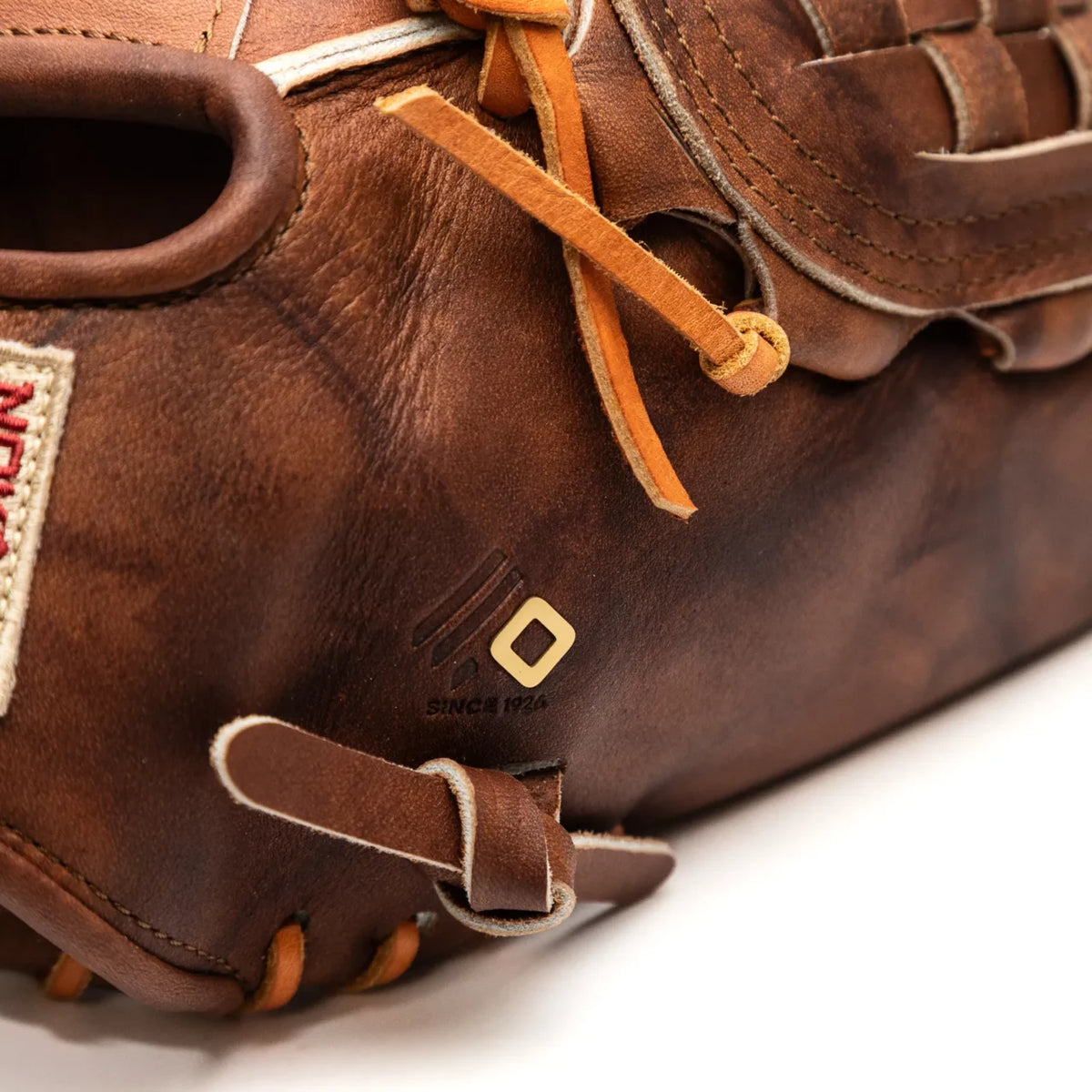 Close-up of a brown Walnut Crunch Nokona Walnut EP 13″ Baseball Glove: W-EP1300C showing the back of the shell, a woven leather web, and a small square logo detail.