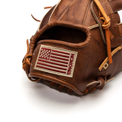 Close-up of a brown leather Nokona Walnut EP 13″ Baseball Glove: W-EP1300H featuring a rectangular patch with a red and white American flag and embroidered text on the wrist strap.