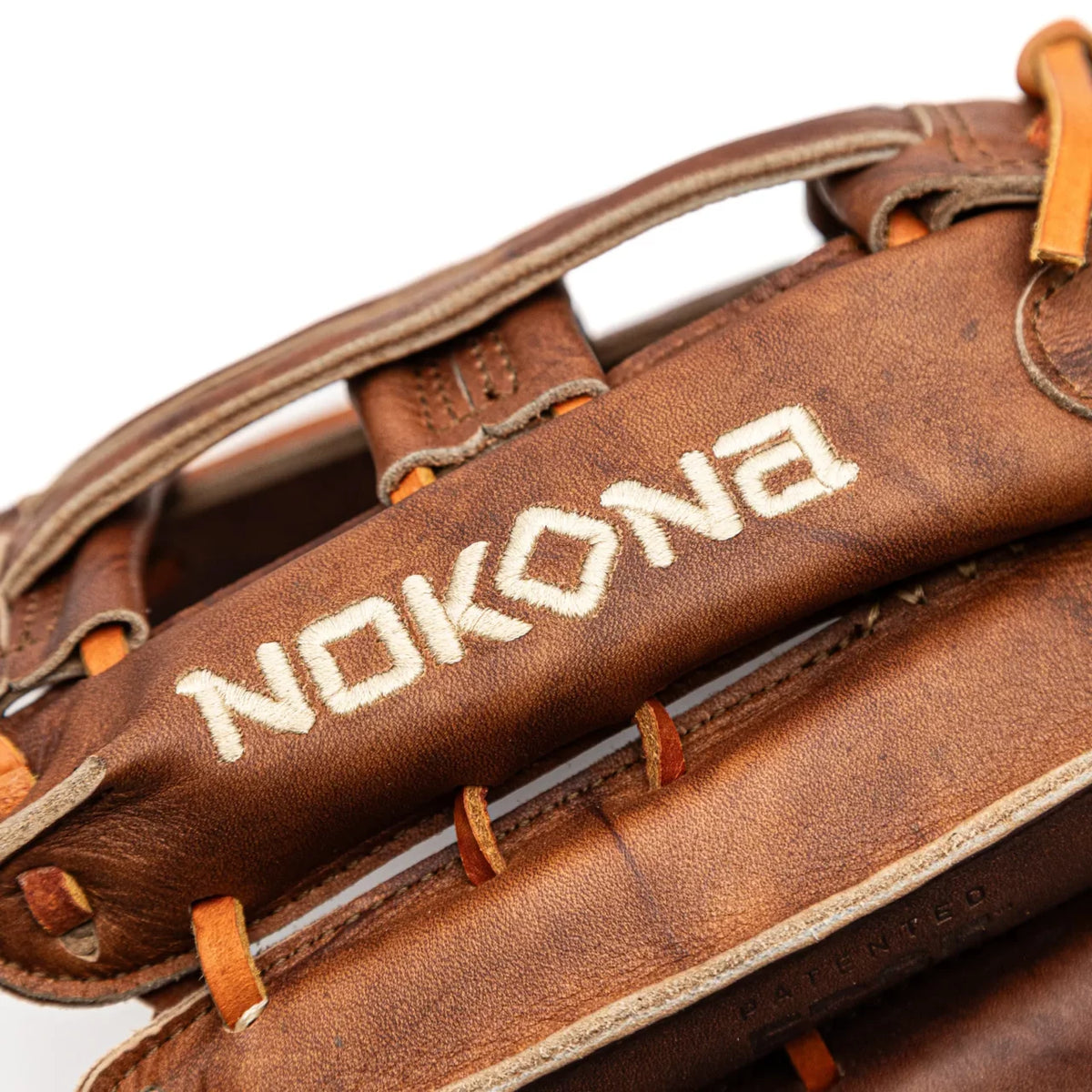 Close-up of a Nokona Walnut EP 13″ Baseball Glove: W-EP1300H outfield glove with the brand name embroidered on the brown leather wrist strap.