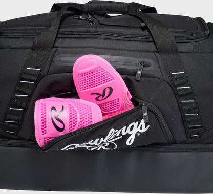 Black Rawlings Yadi 2 Luggage Wheeled Catcher’s Bag: YADI2LUGG with a pair of bright pink shin guards tucked into the front zippered pocket.