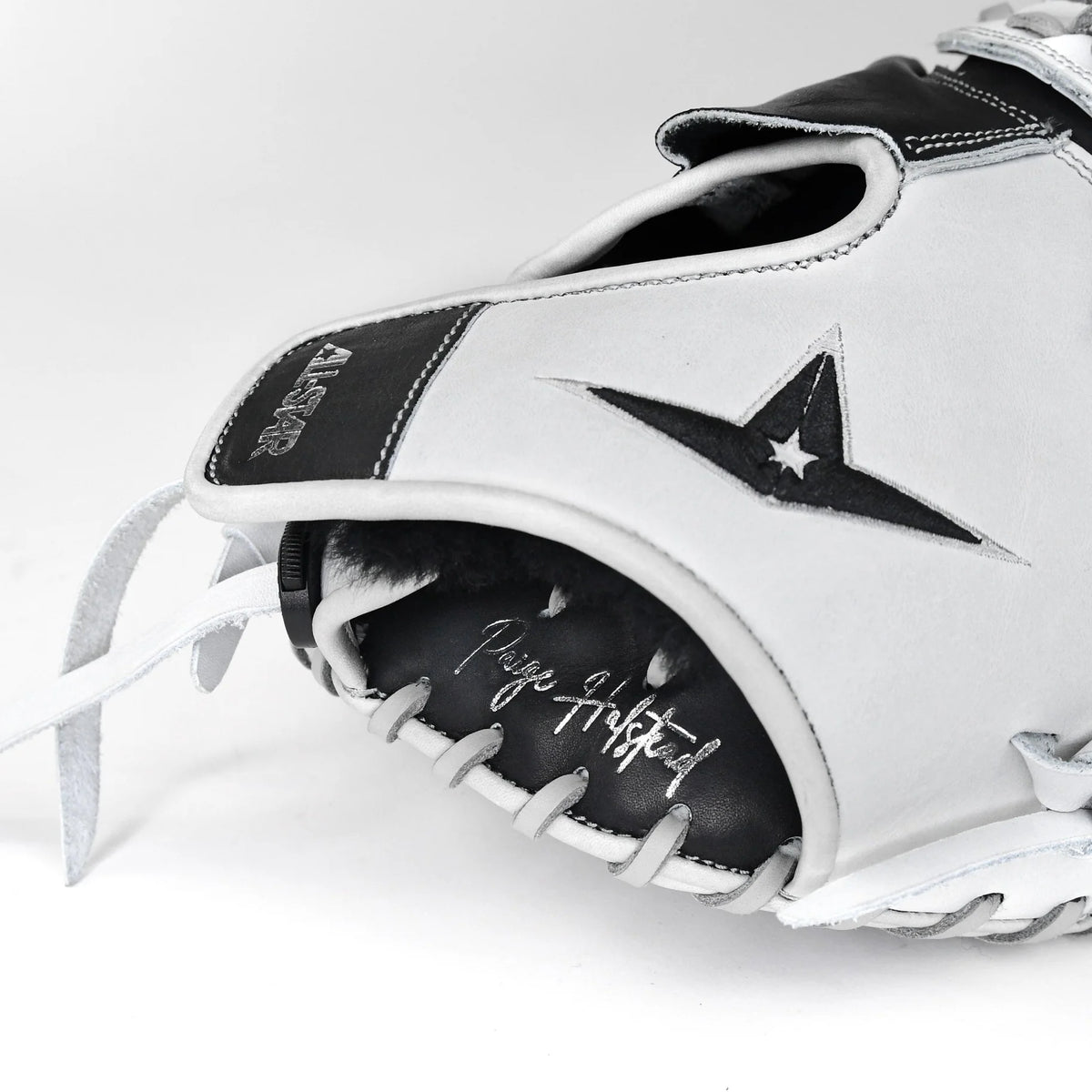 A close-up of the All Star PHX 33″ Paige Halstead Fastpitch Catcher’s Mitt (CMW-PHX-33), a white and black glove featuring the All Star logo, visible stitching, and “Play Grateful” scripted on the palm. This softball catcher’s mitt is designed with an adjustable pocket system to ensure an ideal fit for travel ball players.
