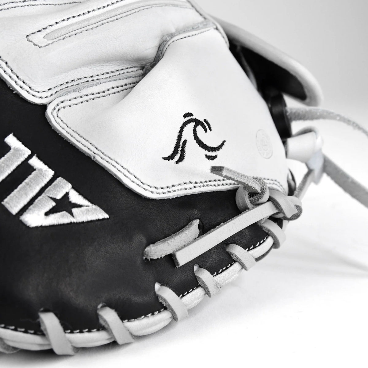 Close-up of the All Star PHX 33″ Paige Halstead Fastpitch Catcher’s Mitt (CMW-PHX-33) in black and white, highlighting its detailed stitching, distinctive wave-like logo on the palm, and an adjustable pocket system designed by All Star for an ideal fit during travel ball play.