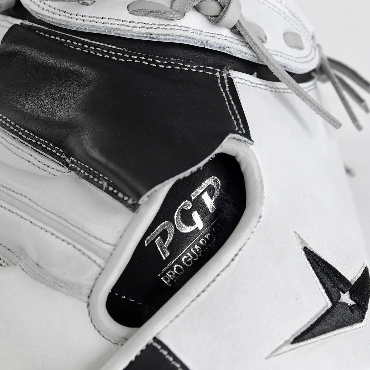 Close-up of the All Star PHX 33″ Paige Halstead Fastpitch Catcher’s Mitt (CMW-PHX-33) in a white and black colorway, with the All Star logo visible inside alongside part of a star-shaped design and gray laces. This mitt features an adjustable pocket system for a customized fit, making it perfect for travel ball and also ideal as a softball catchers mitt.
