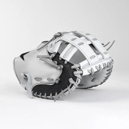 The All Star PHX 33″ Paige Halstead Fastpitch Catcher’s Mitt (CMW-PHX-33) by All Star, featuring a striking white and black design with gray laces, rests on a plain white surface with its pocket and webbing details prominently displayed. Engineered with an adjustable pocket system for an ideal travel ball fit, this mitt seamlessly blends style and performance.